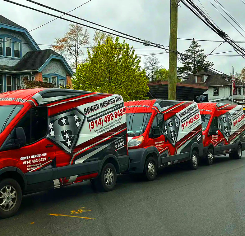 Sewer Heroes Inc van parked curbside with hoses connected to a green inspection tank
